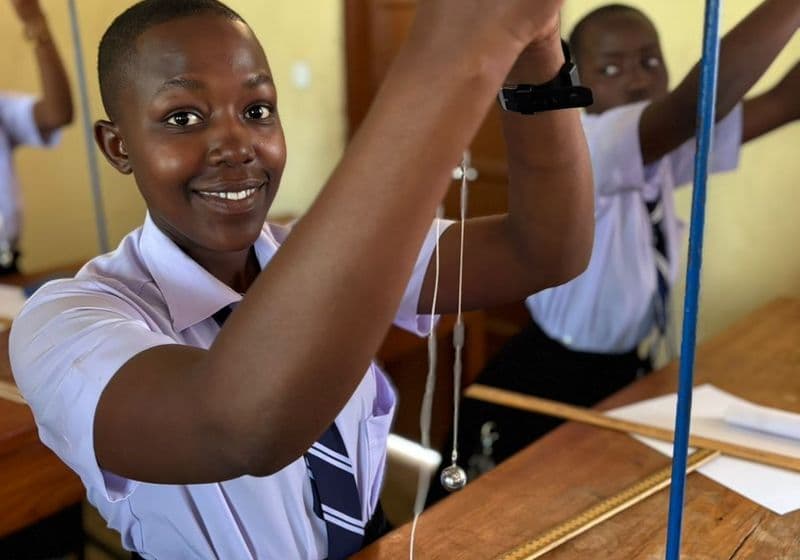 A smiling student using physics apparatus in the Bidii Schools science laboratory