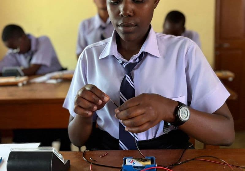A student building and testing an electrical circuit during a physics practical at Bidii Schools