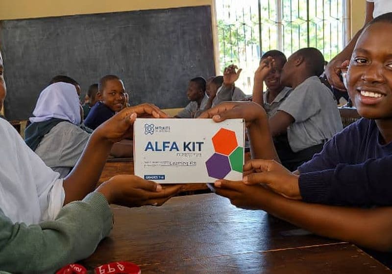 Smiling students posing with a science learning kit at Bidii Schools