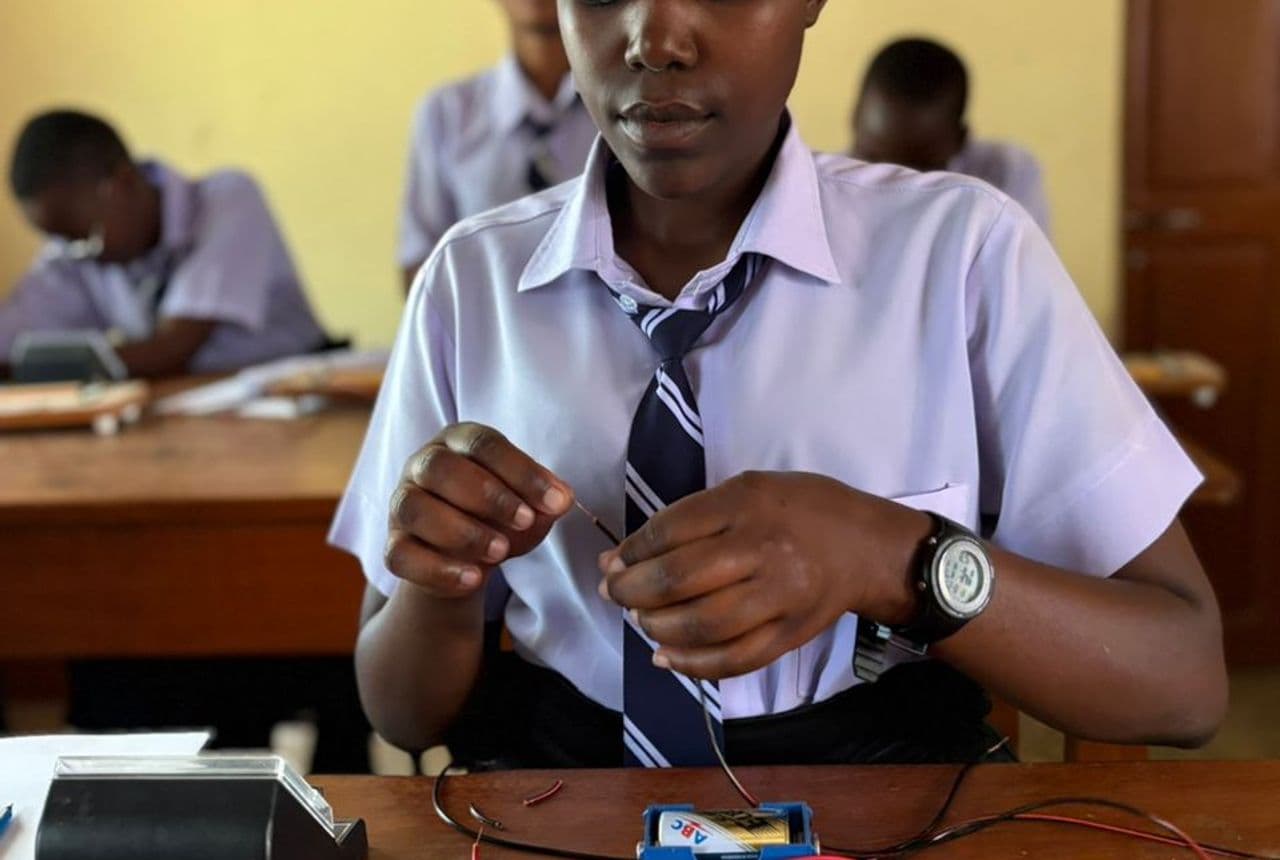 A student building and testing an electrical circuit during a physics practical at Bidii Schools
